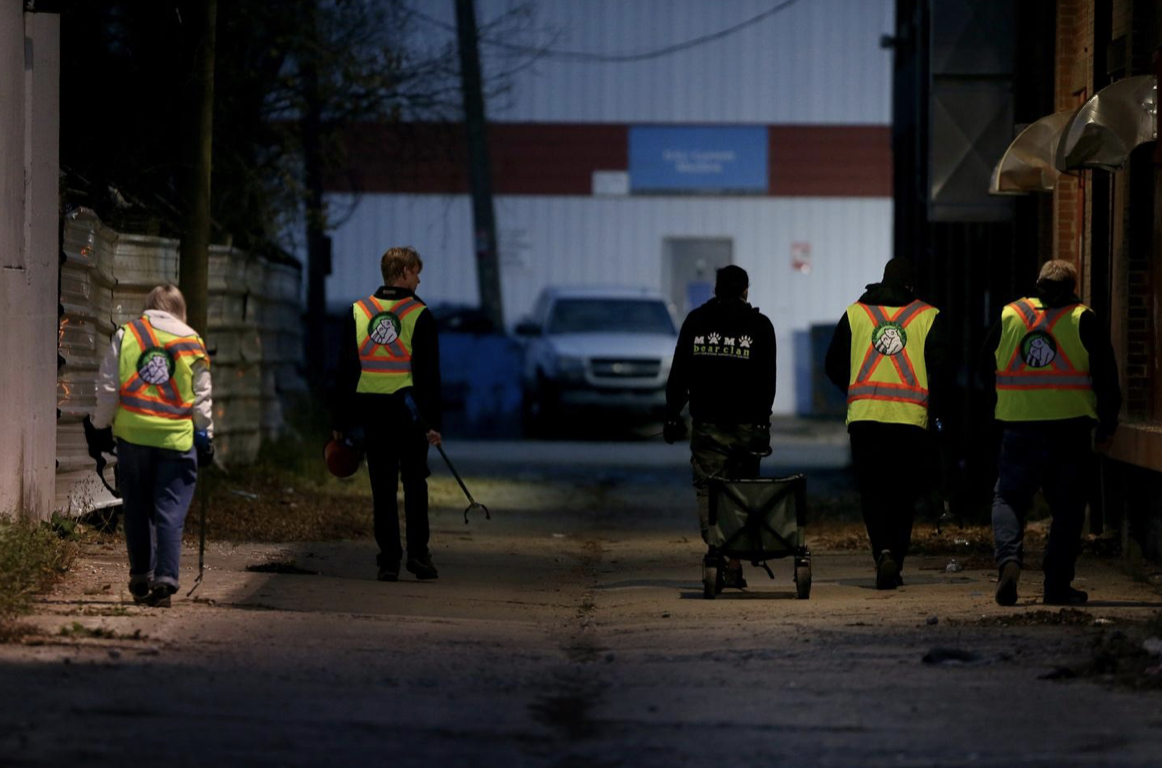Volunteers walk an alley in Winnipeg’s North Point Douglas Neighbourhood.