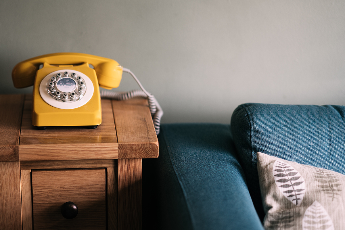 Yellow Phone on side table next to a couch illustrating increasing service demand for children's mental health organizations like Kids Help Phone