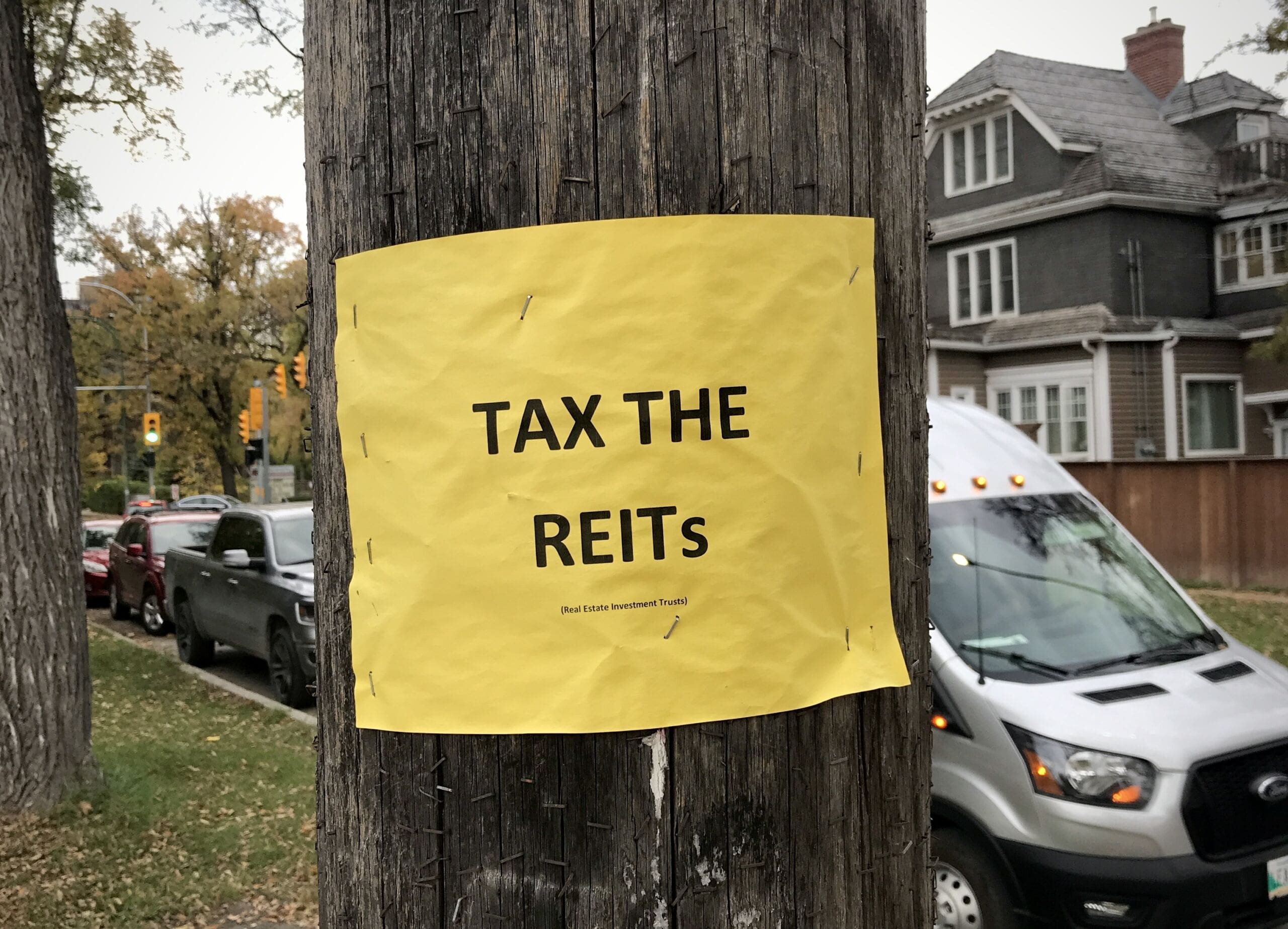 A sign posted in a Winnipeg neighbourhood advocating for higher taxes on Real Estate Investment Trusts. (Shannon VanRaes/Future of Good)