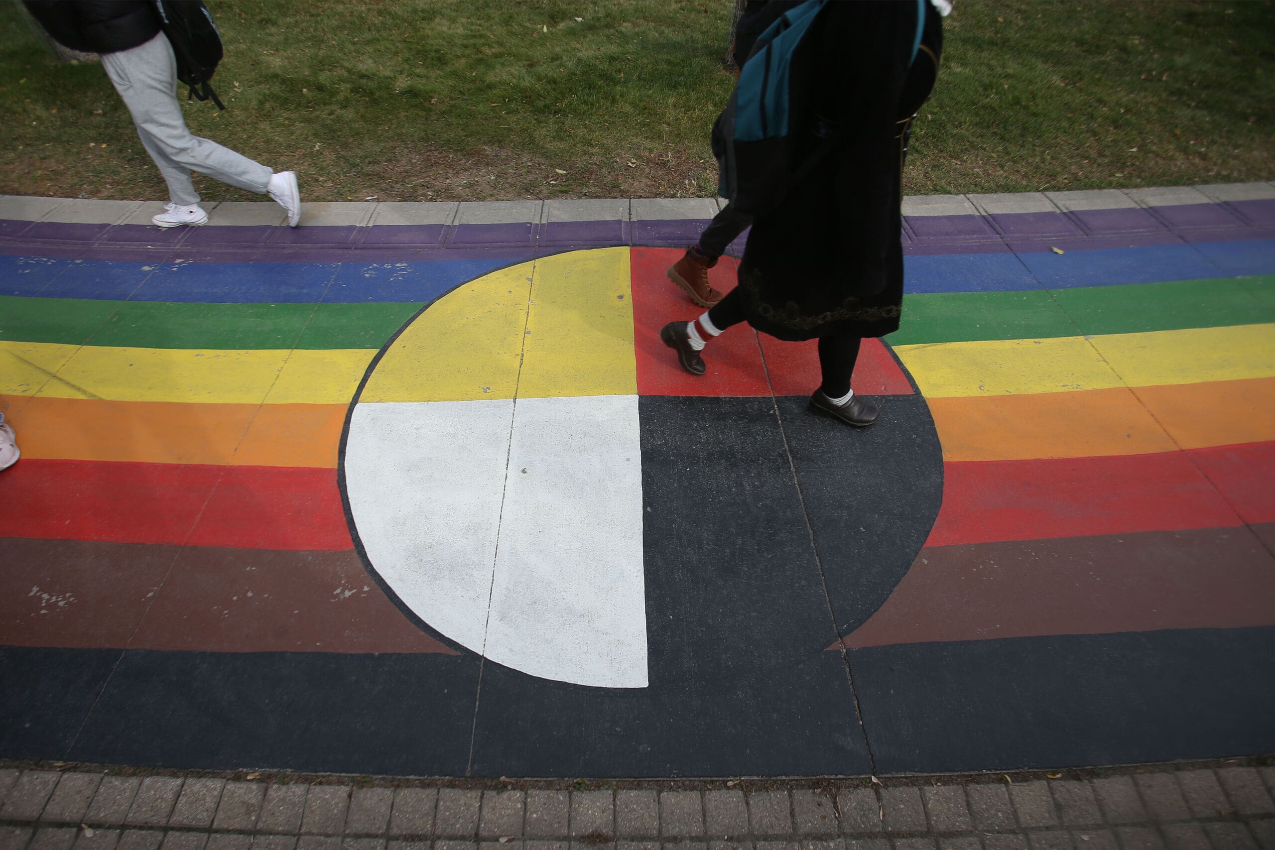 A red, black,yellow and white medicine circle is painted on a brick pathway.