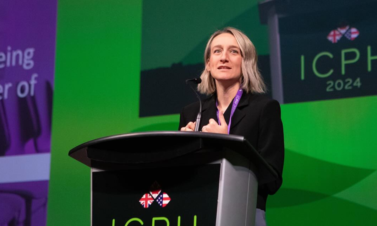Dr. Joss Reimer stands at a podium on a green stage at a conference in Halifax in October of 2024. The President of the Canadian Medical Association says they felt they had no choice but to file a lawsuit to protect trans youth.