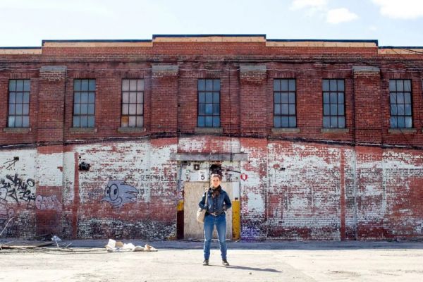 Judith Cayer, project manager, poses in front of what would become Bâtiment 7 in 2017. The empty space was transformed into a community collective of stores and services thanks to blended financing. (Photo courtesy Annik MH from Carufel Le Devoir)