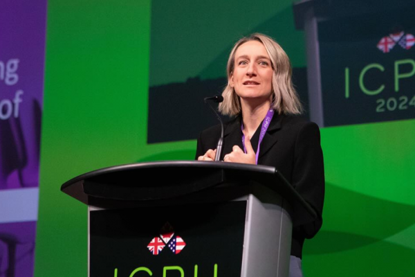 Dr. Joss Reimer stands at a podium on a green stage at a conference in Halifax in October of 2024. The President of the Canadian Medical Association says they felt they had no choice but to file a lawsuit to protect trans youth.