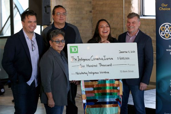 A group of people hold a large cheque for $600,000 with the green TD Bank logo on it.